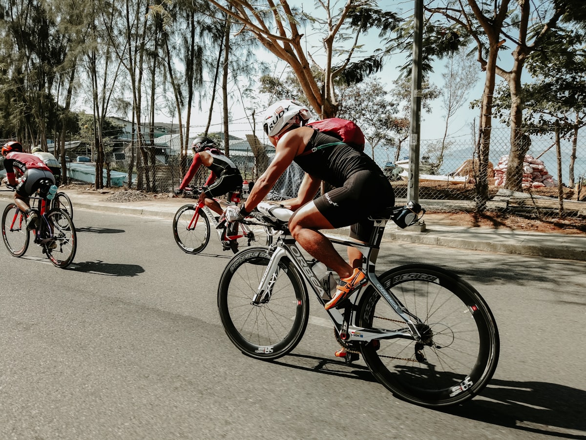 Grupo de ciclistas pedaleando juntos en una ruta arbolada